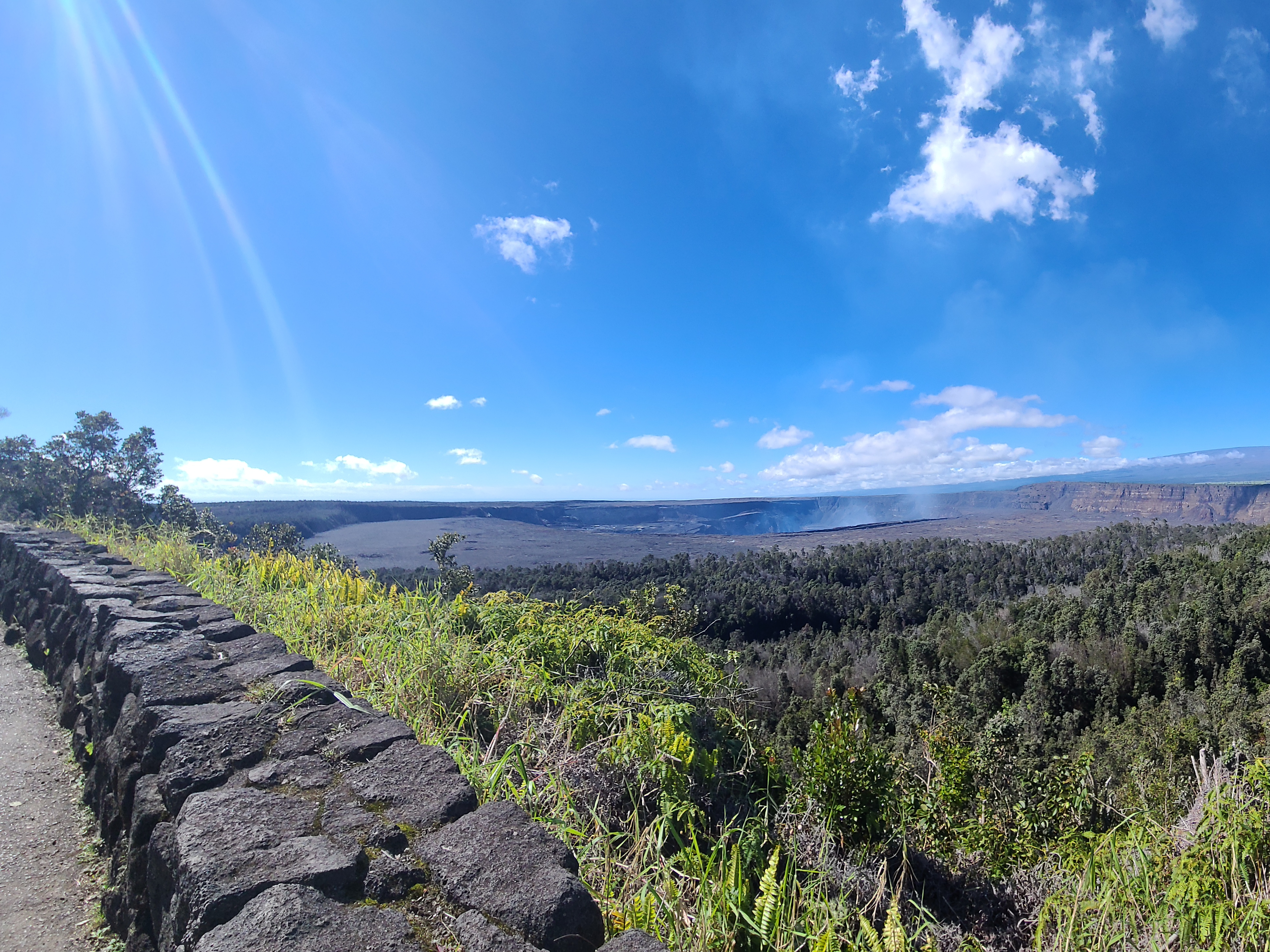 A photo of the Halemaʻumaʻu Crater from behind the Volcano House on the rim trail